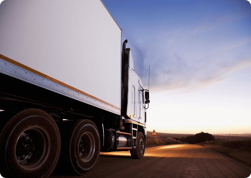 Truck driving on a rural road at dusk.